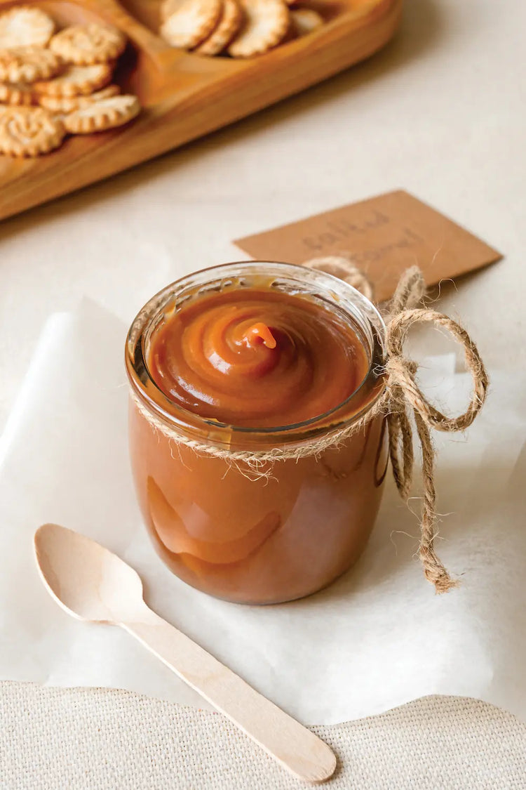 Table sur laquelle sont disposés des gateaux en fond et en premier plan un pot de caramel symbolisant la famille des parfums gourmands.